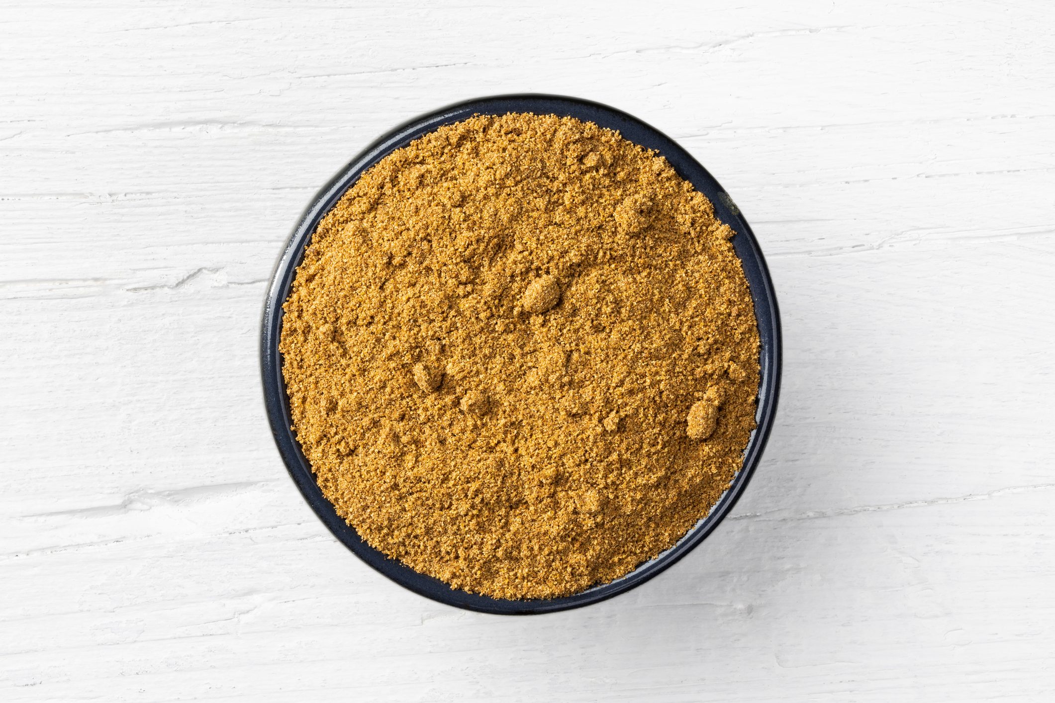 Caraway powder on white wooden background