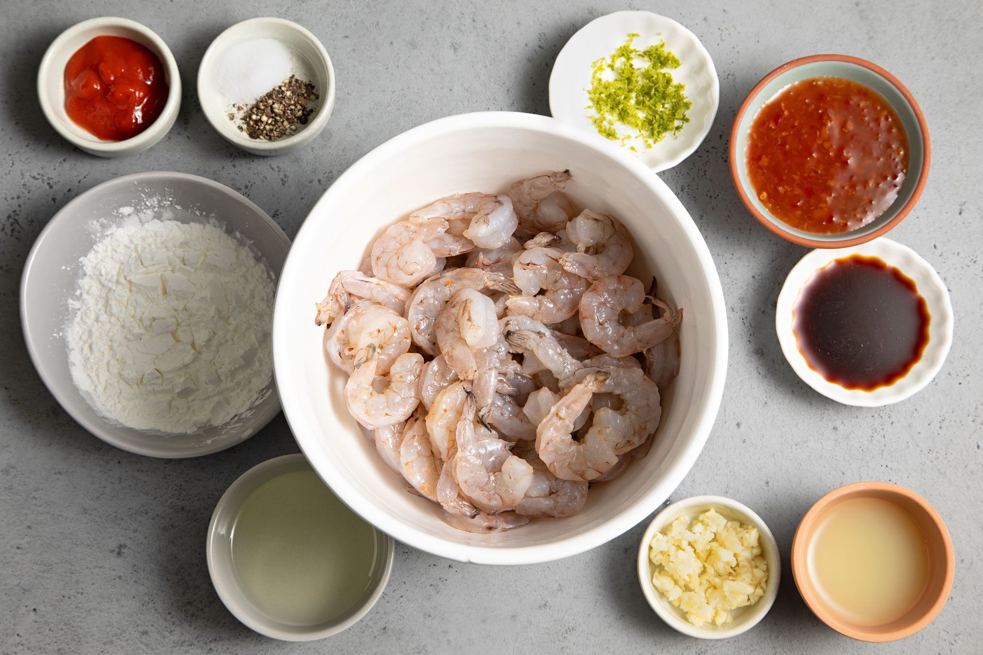 overhead shot of shrimps in a white bowl and other ingredients for Firecracker Shrimp