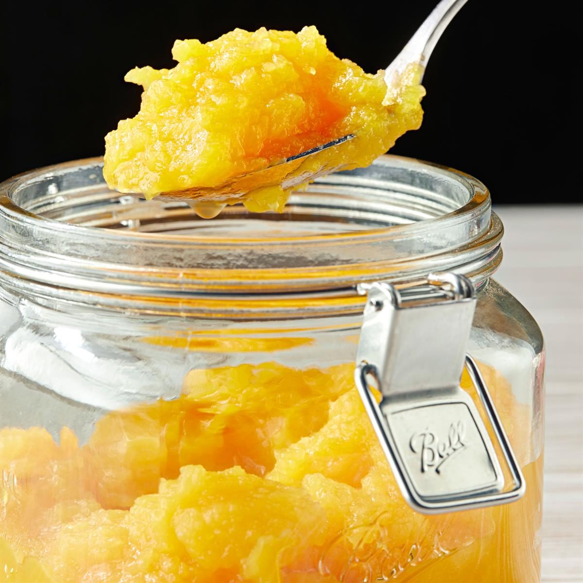 A spoon lifting pumpkin puree from a glass jar.