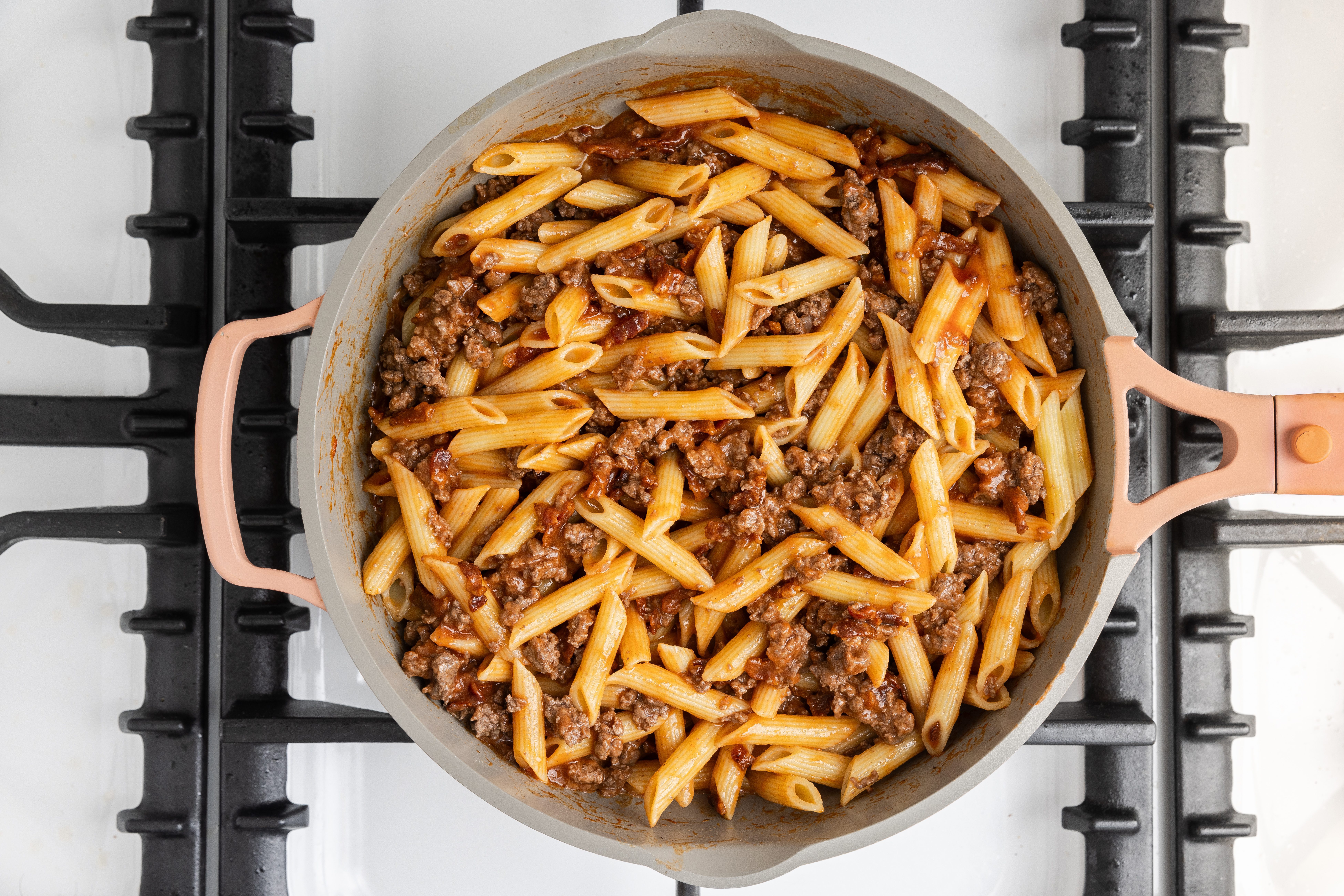 Pasta combined with beef, tomato soup, water and bacon in skillet.