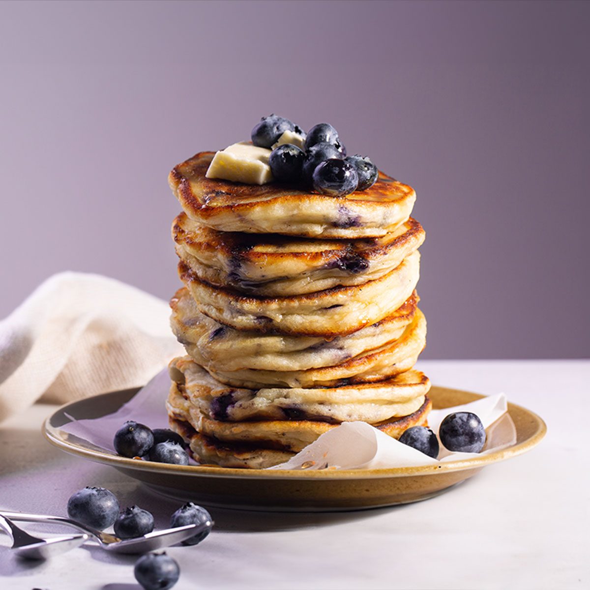 Blueberry Pancakes in a Plate with blueberries and spoon on a table